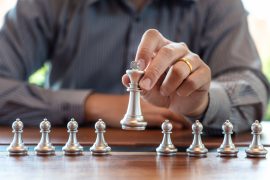 Business man take a king figure checkmate on the chess board game - strategy, management or leadership success concept