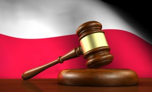 Law and justice of Poland concept with a 3d render of a gavel on a wooden desktop and the Polish flag on background.